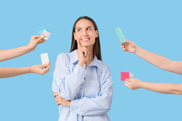 Young woman and hands with contraceptives on blue background