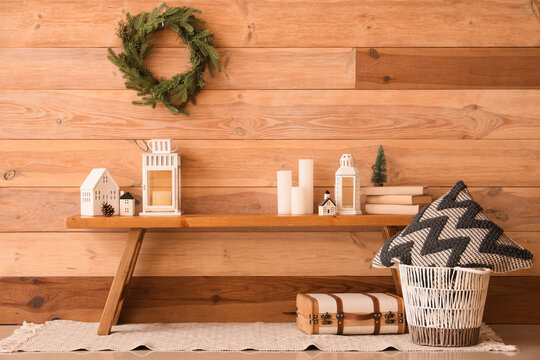 Basket with pillow, suitcase and bench with Christmas decor near wooden wall in room