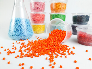 Various colors of masterbatch granules in Erlenmeyer flasks and cups, isolated on white...