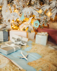 flight as a Christmas present. Toy plane with map with New year eve home decorations cozy long pile carpet under Christmas tree. Boxes gifts for a travel lover. 