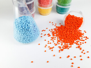 Various colors of masterbatch granules in Erlenmeyer flasks and cups, isolated on white...