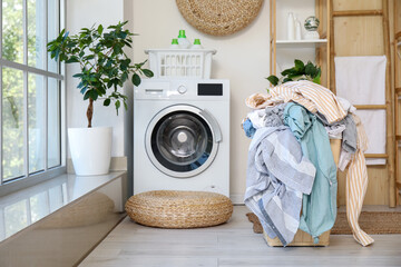 Basket full of dirty clothes in light laundry room © Pixel-Shot