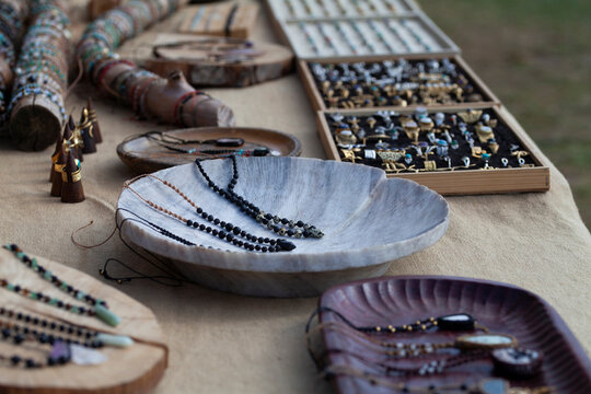 Handmade jewelry stall with bracelets, rings, and necklaces displayed on a rustic wooden backdrop. Unique, artisanal pieces.