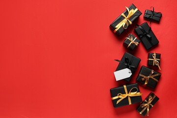 Gift boxes with blank paper tag on red background. Black Friday sale