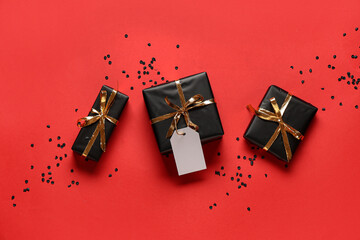 Gift boxes with blank paper tag and confetti on red background. Black Friday sale