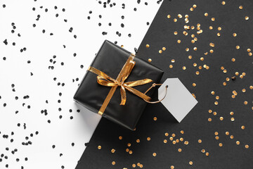 Gift box with blank paper tag and confetti on color background. Black Friday sale