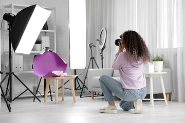 Female African-American photographer with camera working in studio, back view