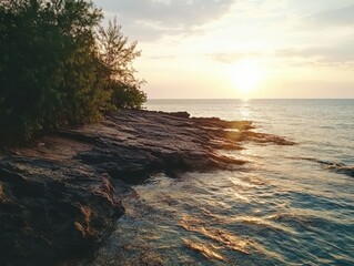 Obraz premium Golden hour light bathes rocky shoreline at sunset, creating a serene landscape.