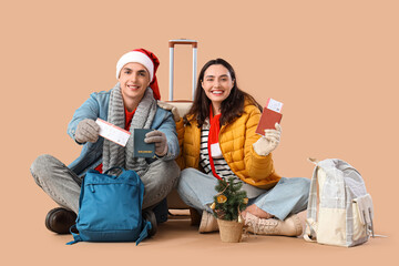 Cute young couple with passports, tickets and backpacks on beige background. Winter vacation concept