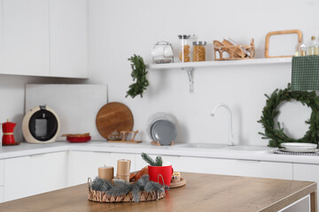 Candles, fir branches and cup of hot chocolate on table in festive kitchen. Christmas celebration