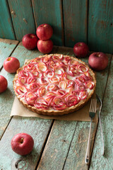 Apple rose pie with fresh apples around on a background of old boards