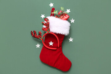 Christmas sock with reindeer horns,  mistletoe twig and gift on green background. Top view