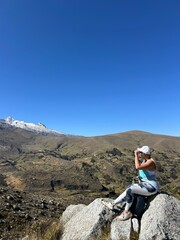 Fototapeta premium Woman traveler siitng at a mountain scenery with a glacier in a background