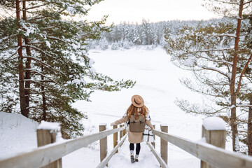 Smiling woman walks near a winter lake. She is enjoying the beautiful winter weather. Nature, travel, winter holidays.