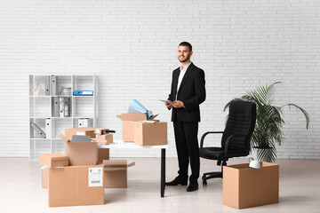 Young businessman with cardboard boxes in office on moving day