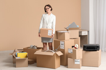 Fototapeta premium Young businesswoman packing things in office on moving day