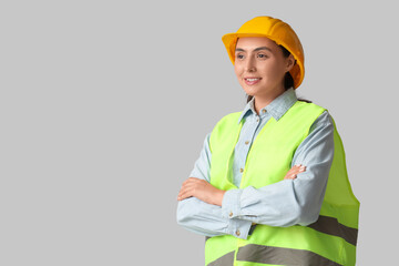 Young female construction worker on grey background. Woman in male profession concept