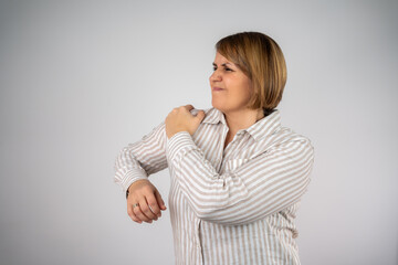 Obraz premium Pain in the shoulder. Upper arm pain, People with body-muscles problem, Healthcare And Medicine concept. Attractive woman standing isolated and holding painful shoulder with another hand.