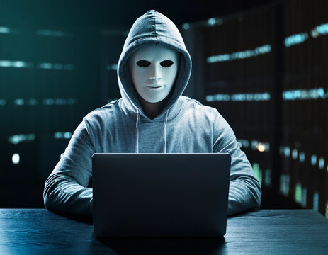 a hacker with a mask on his face in front of a laptop