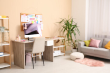 Fototapeta premium Blurred view of designer's office with workplace, sofa and shelf units