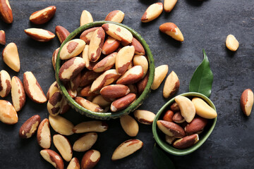 Bowls with tasty Brazil nuts on black background