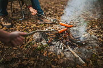 close up of sausage on wood stick grill on the camp fire