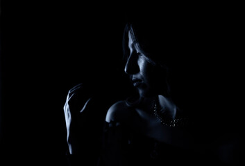 Naklejka premium Portrait of a mysterious silhouette of a young woman standing on a blue glowing background