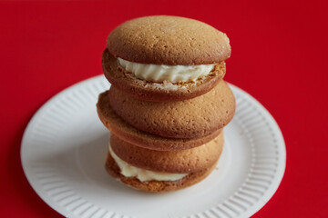 Pumpkin pies stacked on top of each other on a white disposable plate against a red background, pumpkin pies arranged in a tower on a white plate against a red background, traditional desserts.