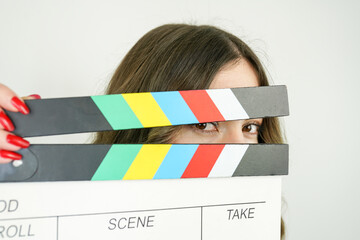 Woman portrait holding movie clapper against colorful white background.