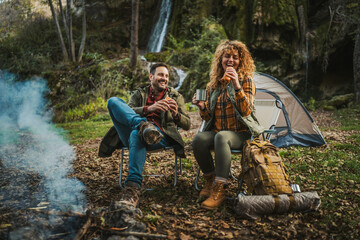 happy couple have fun while eating hot dogs on camping in the woods