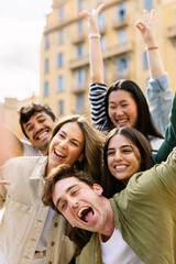 Vertical shot of young group of happy people enjoying time together at city street. Millennial generation friends having fun, laughing while enjoying holiday trip. Friendship and youth concept