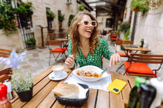 Fototapeta Woman eating italian pasta and drinking coffee at restaurant on the street in Rome. Concept of Italian gastronomy and travel.