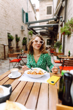 Fototapeta Woman eating italian pasta and drinking coffee at restaurant on the street in Rome. Concept of Italian gastronomy and travel.