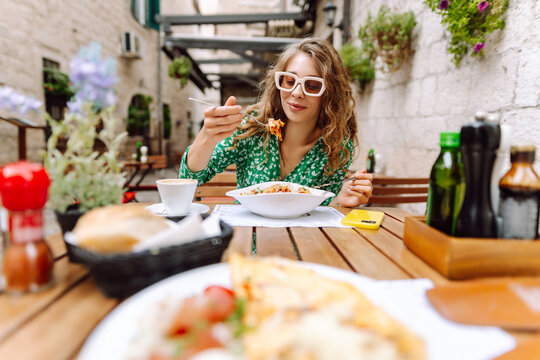 Fototapeta Woman eating italian pasta and drinking coffee at restaurant on the street in Rome. Concept of Italian gastronomy and travel.