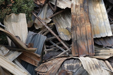 View on corrugated aluminium  sheets damaged by fire. The metal is distorted with traced of smoke and can only be used as scrap. The capture is suitable as background. 