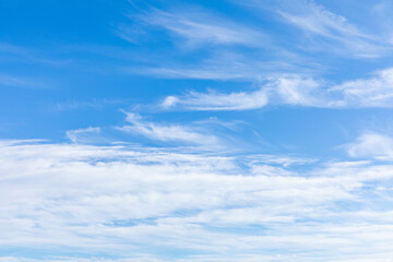 Blue sky with fluffy white cirrus clouds. The sky is clear and bright, and the clouds are scattered throughout the sky. Scene is peaceful and serene, copy space. High quality photo