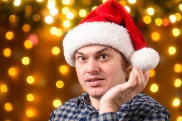 A man face, poses in New Year decorations with festive illumination and garlands, Christmas lights and decorations background, Holiday theme