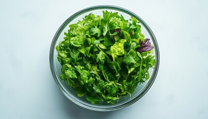 Freshly washed mixed greens in a clear bowl ready for meal preparation in the kitchen