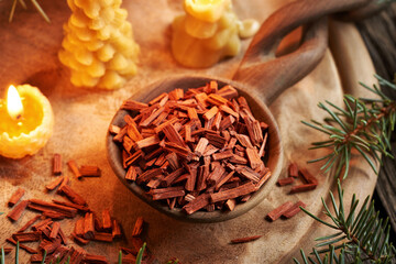 Red sandalwood chips on a wooden spoon with beeswax candles