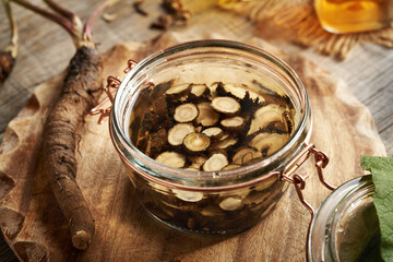 Preparation of homemade herbal tincture from fresh burdock root and alcohol in a jar