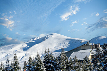 Bursa Uludağ ski resort, blue sky with white clouds in the background, snowy mountain peak, chair lift, hotels and winter sports