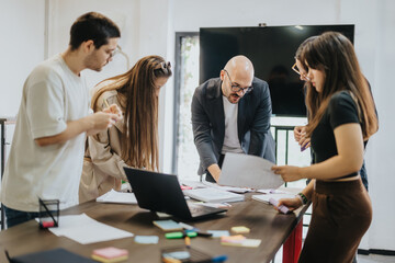A group of students collaborates with their professor on a project in a modern classroom setup. The...
