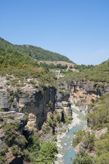 Osumi Gorge, Albania - August 15 2024: Stunning view of Osumi Canyon (Albanian: Kanioni i Osumit), showcasing the breathtaking cliffs, vibrant greenery, and winding river through dramatic landscape.