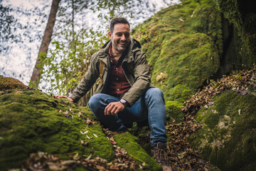 Adult man hiker descend and explore scenic forest around rocks outdoor