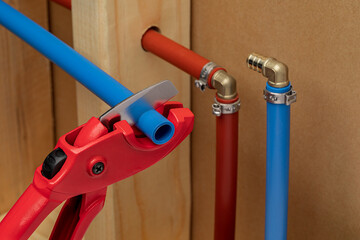 Cutting and installing PEX plastic water supply plumbing pipe in wall of house. Home repair,...