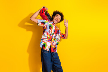 Portrait of nice funky young man boombox arm wave wear shirt isolated on vibrant yellow color background