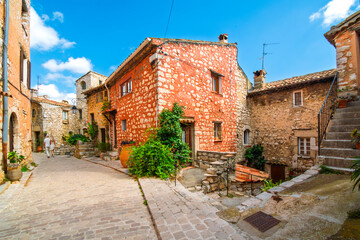 A couple walks past narrow alleys and winding streets in the medieval stone village of Tourrettes-Sur-Loup, France.