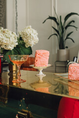 pink heart cakes, cocktails, flowers on gold trunk table indoors