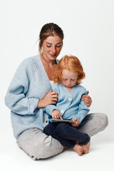 Mother and daughter engaged in digital learning together with a tablet on the floor