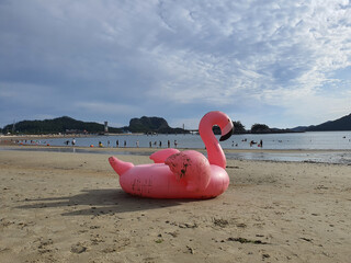 해변가의 더러워진 핑크색 플라밍고 튜브